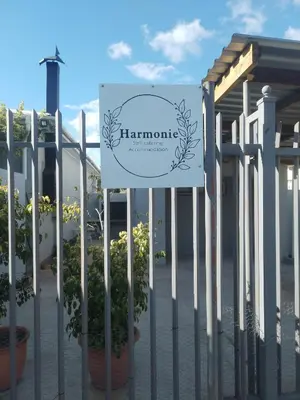 a sign on a fence with potted plants at Harmonie Self Catering in Wolseley