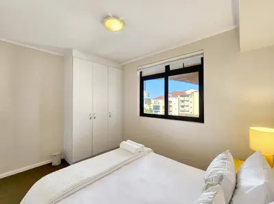 a bedroom with a bed and a window at Walkable, pools, park and great for families in Cape Town