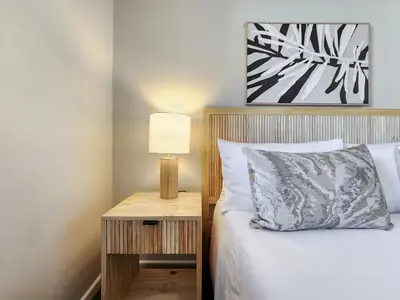 a bedroom with a bed and a table with a lamp at Walkable, pools, park and great for families in Cape Town