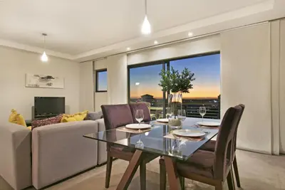 a dining room with a table and a couch at Manhattan 1003 in Cape Town