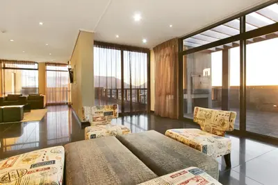 a room with two beds and chairs and a living room at Manhattan 1003 in Cape Town