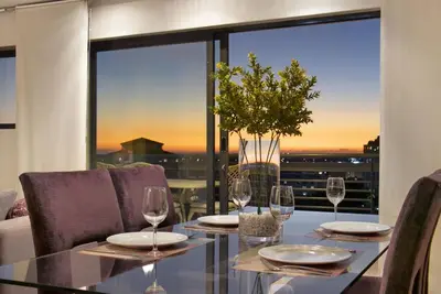 a dining room table with wine glasses and a view at Manhattan 1003 in Cape Town