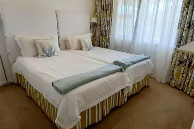 a bed with white sheets and pillows in a bedroom at 305B Bayview Breathe in Hermanus