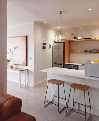 a kitchen with a white counter and two stools at Apartment at Hermanus Waterfront in Hermanus