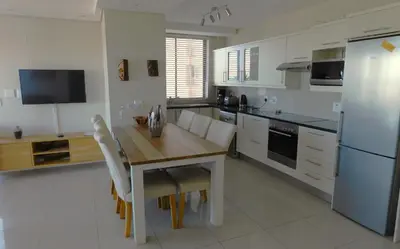 a kitchen with a wooden table and a refrigerator at 97 On Strand in Strand