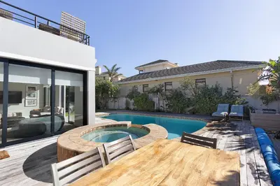 a backyard with a pool and a table and chairs at Sunset Villa 50 in Cape Town