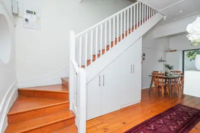 a staircase in a home with white walls and wooden floors at Enchanting Abode in Rosebank in Cape Town
