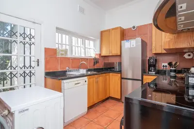 a kitchen with wooden cabinets and a white refrigerator at Enchanting Abode in Rosebank in Cape Town
