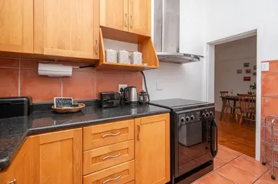a kitchen with wooden cabinets and a stove at Enchanting Abode in Rosebank in Cape Town