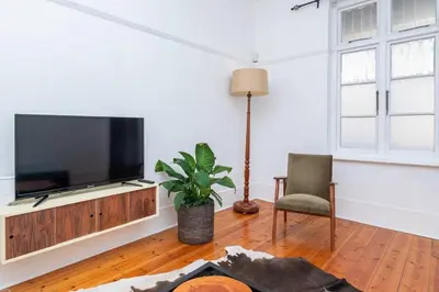 a living room with a flat screen tv and a chair at Enchanting Abode in Rosebank in Cape Town