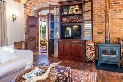a living room with a tv and a brick wall at Serendipite Villa in Franschhoek
