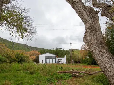 a white house in a field with a tree at Die Stal in Worcester