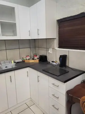 a kitchen with white cabinets and a black counter top at 9 on Oostersee in Cape Town