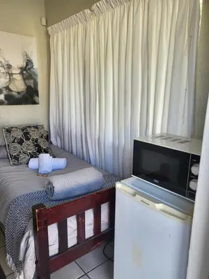 a bedroom with a bed with a television on a dresser at 9 on Oostersee in Cape Town