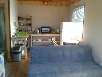 a living room with a blue couch and a refrigerator at Little Lotta Cottage in Caledon