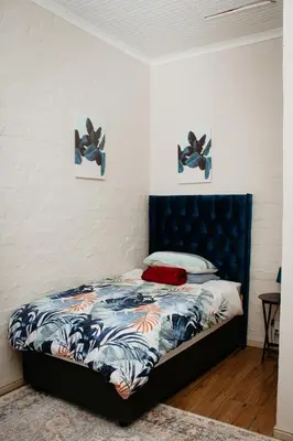a bed with a blue headboard in a room at Mooi Uitsig Lodge in Paarl