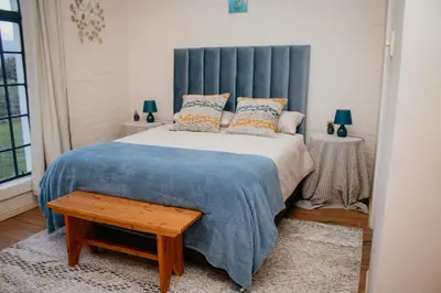 a bedroom with a large bed with a blue headboard at Mooi Uitsig Lodge in Paarl