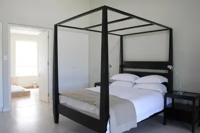a bedroom with a black canopy bed with white pillows at La Terra de Luc in Franschhoek