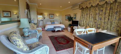 a living room with a bedroom with a bed and chairs at Roosboom Guest Apartments in Somerset West