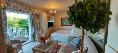 a living room with a bed and a living room with a plant at Roosboom Guest Apartments in Somerset West