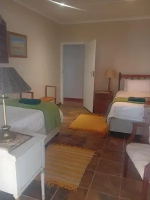 a bedroom with two beds and a lamp on a table at Out of Africa in Sandbaai, Hermanus in Hermanus