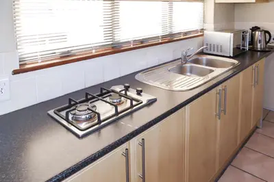 a kitchen counter with a stove and a sink at Shalom Self Catering in Kleinmond