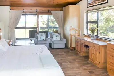 a bedroom with a large white bed and two chairs at Shalom Self Catering in Kleinmond