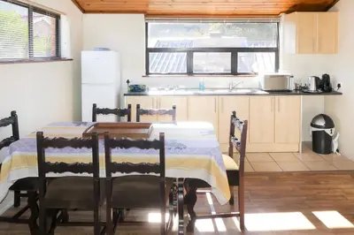 a kitchen with a table and chairs and a refrigerator at Shalom Self Catering in Kleinmond