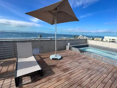 a patio with an umbrella and a chair and a pool at Waterfront Studio apartment no 5 in Hermanus