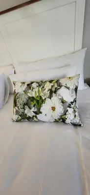 a pillow with white flowers on a bed at Audrey's Self-Catering Accommodation in Cape Town