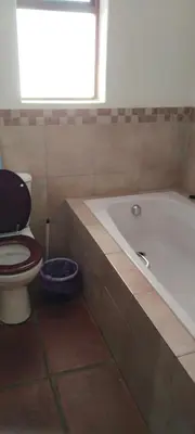 a bathroom with a tub and a toilet and a window at The 10th Hole - Golf Estate in Villiersdorp