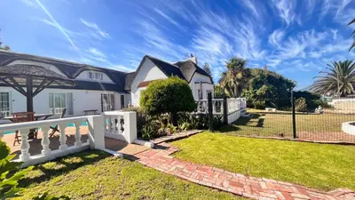 a house with a white fence and a yard at Lagoon Lodge in Cape Town