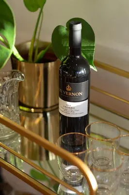 a bottle of wine on a glass table with glasses at Mount Vernon Manor in Klapmuts