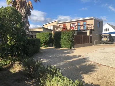 a house with a driveway in front of it at Fisherhaven Travellers Lodge in Hermanus