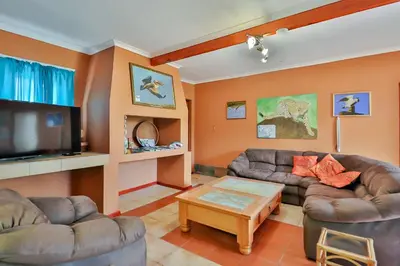 a living room with two couches and a tv at Fisherhaven Travellers Lodge in Hermanus