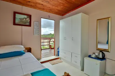 a bedroom with a bed and a large window at Fisherhaven Travellers Lodge in Hermanus