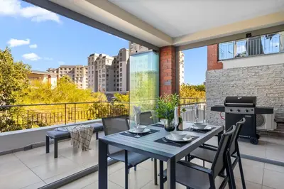 a balcony with a table and chairs and a grill at Mayfair Luxury 212 by Host Agents in Cape Town