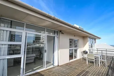 a house with a deck with a table and chairs at 6 Culemborg Court, 5 Culemborg Street, Strand, Cape Town in Cape Town