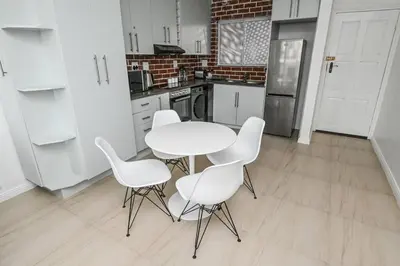 a kitchen with a white table and white chairs at 6 Culemborg Court, 5 Culemborg Street, Strand, Cape Town in Cape Town