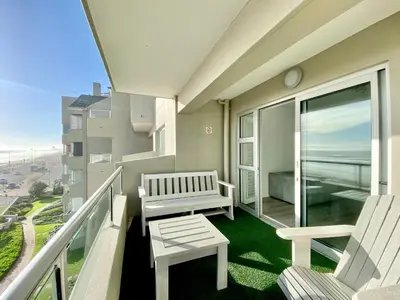 a balcony with two chairs and a bench on it at Sea Spray Blouberg Beach in Bloubergstrand