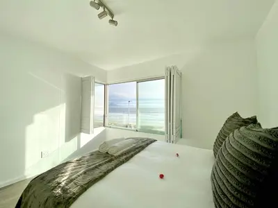 a bedroom with a large bed with a view of the ocean at Sea Spray Blouberg Beach in Bloubergstrand