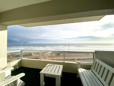 a balcony with a bench and a view of the beach at Sea Spray Blouberg Beach in Bloubergstrand