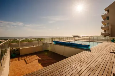 a balcony with a swimming pool on top of a building at Sea Spray Blouberg Beach in Bloubergstrand