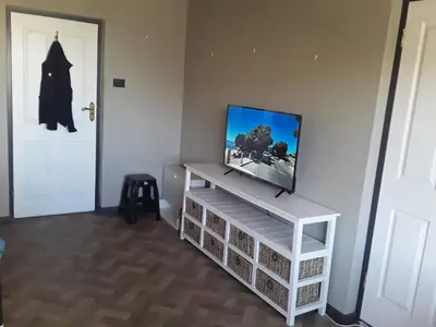 a flat screen tv sitting on top of a white entertainment center at Beach Haven Sea Views, Fritzandi, Strand, Cape Town in Cape Town