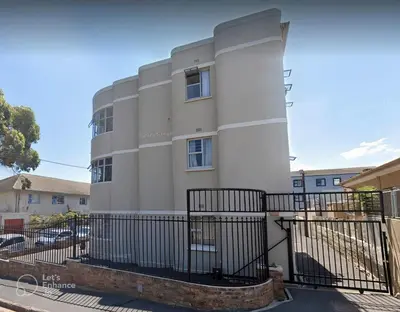 a white building with a black fence at Beach Haven Sea Views, Fritzandi, Strand, Cape Town in Cape Town