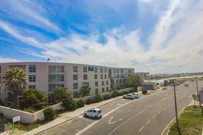 a street with a building and cars on a road at Luxury Beach Escape Sleeps 4 - Ocean View - Spa - Pool - Gym - Back Up Power in Cape Town