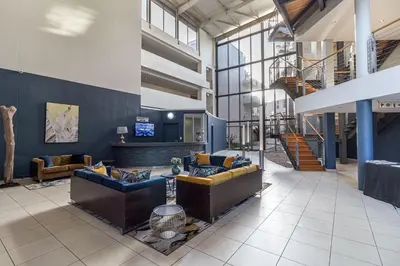 a lobby with couches and a staircase in a building at Luxury Beach Escape Sleeps 4 - Ocean View - Spa - Pool - Gym - Back Up Power in Cape Town