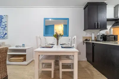 a kitchen with a table and chairs in a room at Luxury Beach Escape Sleeps 4 - Ocean View - Spa - Pool - Gym - Back Up Power in Cape Town