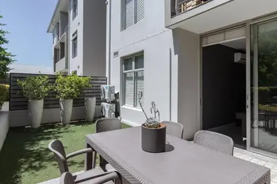 a patio with a table and chairs on a balcony at Modern Family Flat Andringa Walk in Stellenbosch