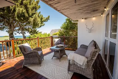 a porch with chairs and a table on a deck at Klein Paradys in Kleinmond
